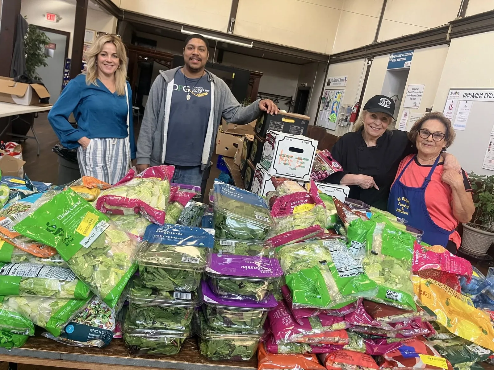 St. Brigid's volunteers behind a table piled with donated fresh greens.